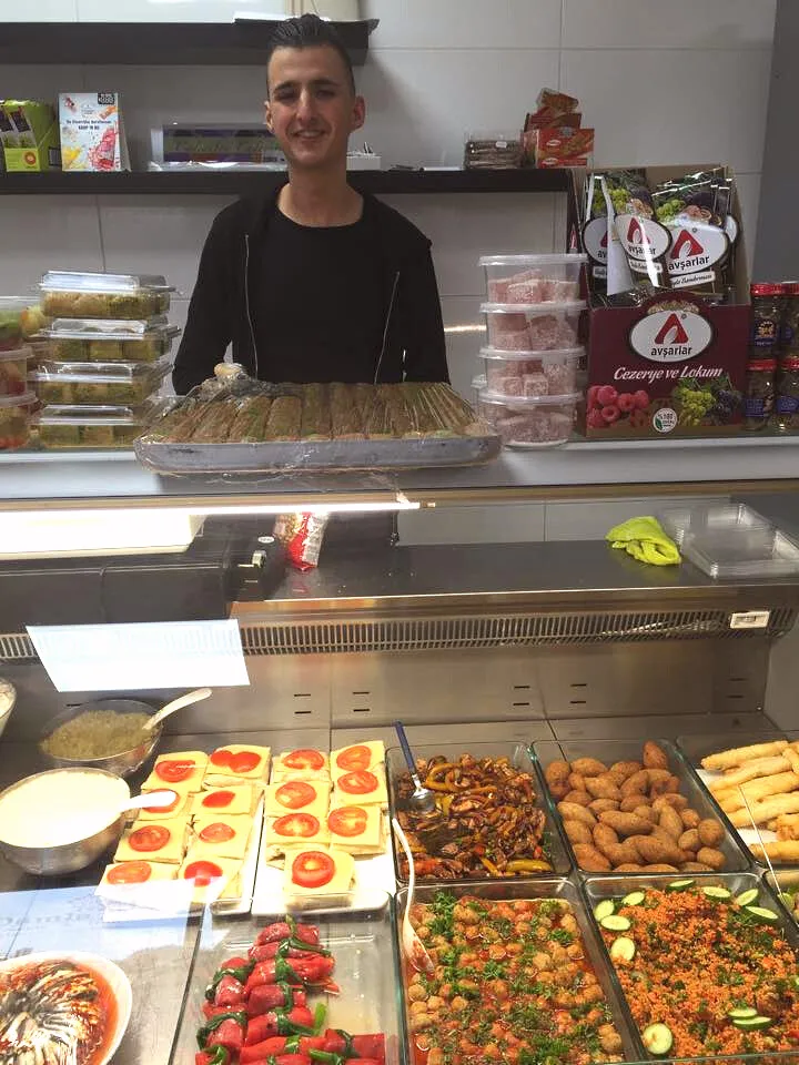 Medewerker van Damla achter de toonbank met verse salades en delicatessen